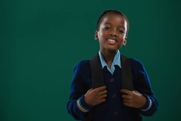 School girl with backpack standing against chalk board Smiling school girl with backpack standing against chalk board school uniform stock pictures, royalty-free photos & images