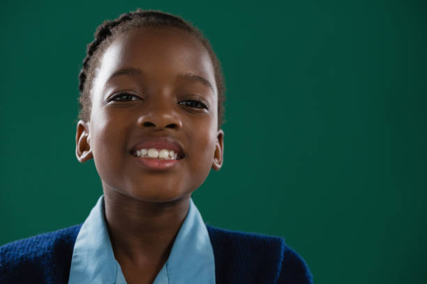 istock Smiling schoolgirl standing against green background 823846590