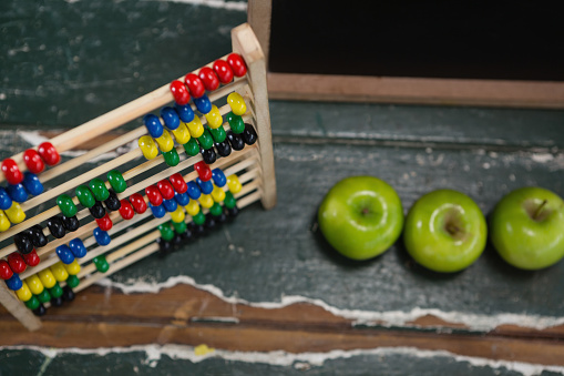 Close-up of abacus and green apples on wooden table