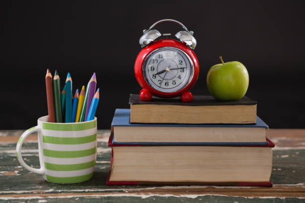 istock Alarm clock and apple on stack of books with pen holder 823847648