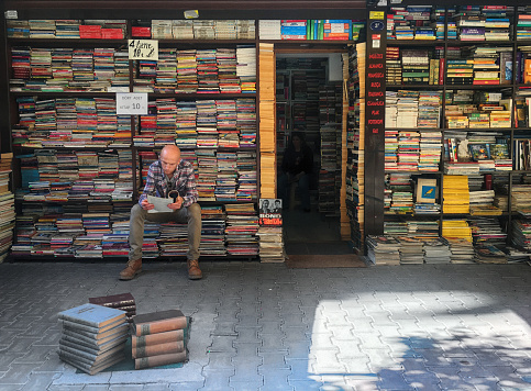 Image has been captured from outside of the store. A local turkish man sitting in front of the store and reading some paper. Image has been captured from outside of the store on 1440th Street in Alsancak, Izmir. The Name of the Store is \