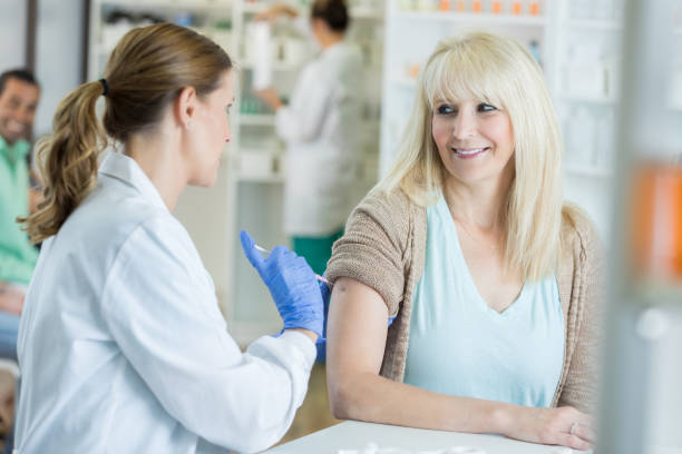 istock Pharmacist pushes needle into arm of smiling patient during flu shot 823870528