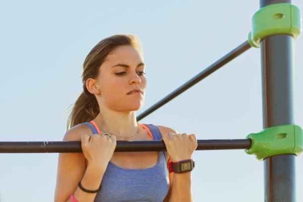 istock Female athlete doing chin-ups on bar against sky 823876364