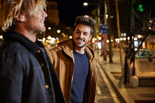 Happy man talking to friend in city at night