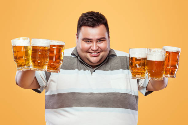 istock Young fat man at Beer Fest, drinking beer on yellow background. 823887014