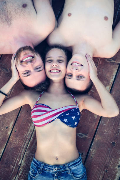 istock Embraced Smiling Friends Lying on Wooden Pier and Sunbathing 823891336