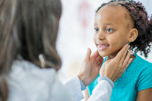 Checking her Lymph Nodes A young girl of African descent is at the doctor's office getting a checkup. Her and her doctor both smile as the medical professional checks her lymph nodes. lymphoma photos stock pictures, royalty-free photos & images