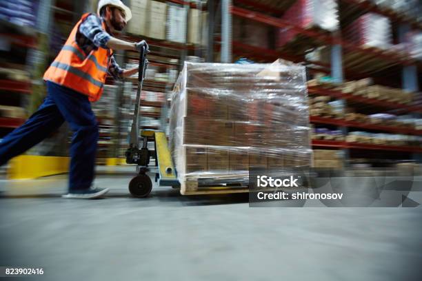 Worker Moving Retail Merchandise In Large Warehouse Stock Photo - Download Image Now