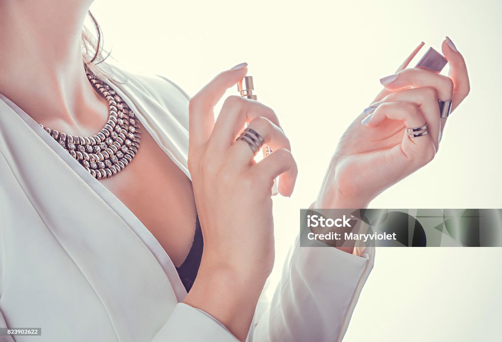 Woman applying perfume on her wrist Woman in red dress applying perfume on her wrist Perfume Stock Photo