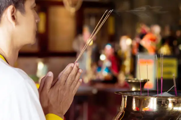 Photo of Man praying for new year ,lighting incense to Buddha.
Burning joss stick and oil palm candle at chinese shrine for making merit in chinese new year festival. 
May his life be blessed with health  and happiness all through.