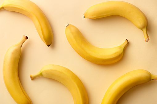 Banana pattern on a yellow background. Exotic fruit repetition viewed from above. Top view.