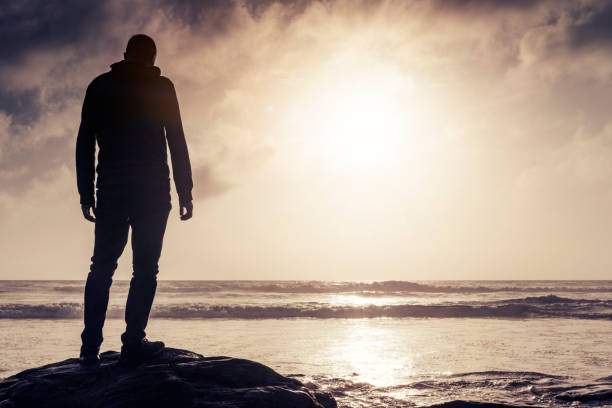 istock Man Stood on a rock looking out over a Sunset. 823917920