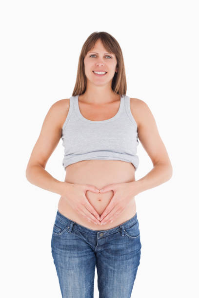 istock Lovely pregnant female posing while forming a heart with her hands 823920888