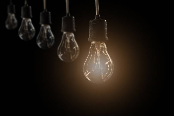 istock Hanging light bulbs with glowing one on dark background. Idea and creativity concept with light bulbs. 823921196