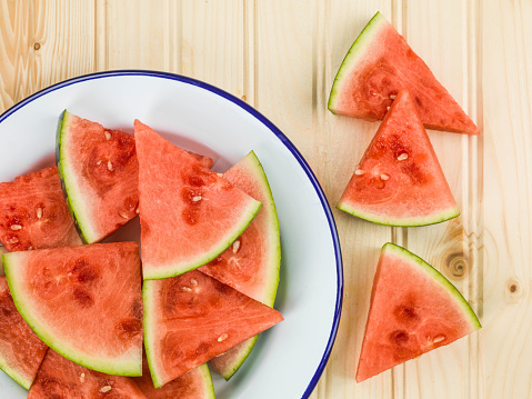 Plate of Cut Watermelon Segments Against a Light Pine Wood Background