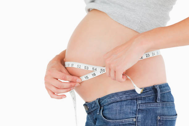 istock Pregnant woman measuring her belly while standing 823924344