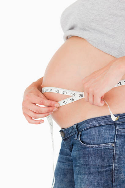 istock Pregnant woman measuring her belly while standing 823924454