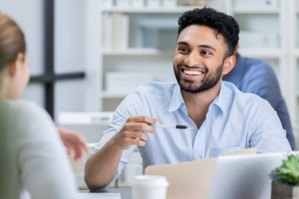 istock Young businessman laughs with unrecognizable coworker across table 823925562