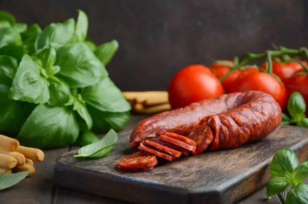 Chorizo sausage. Spanish traditional chorizo sausage with fresh herbs and tomatoes, selective focus