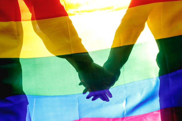 人、同性愛、同性結婚、同性愛者とコンセプトが大好き - ハグ、虹色の旗を保持している幸せの男性の同性愛者のカップルのクローズ アップ - two flags ストックフォトと画像