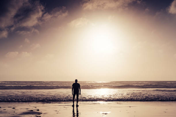 Man stood on a Watergate Bay Beach, Newquay, Cornwall near sunset after a run along the beach.