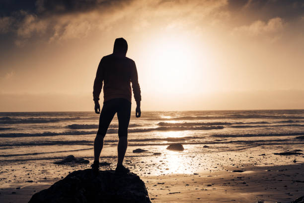 istock Man stood on a Beach near sunset after a run along the beach. 823932244