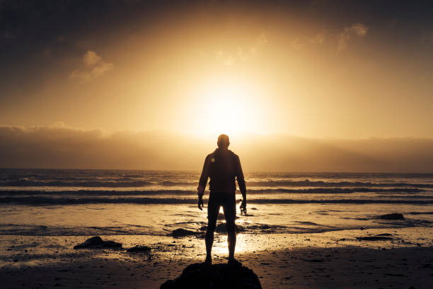 istock Man stood on a Beach near sunset after a run along the beach. 823932262
