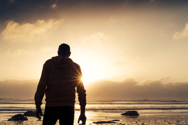 istock Man stood on a Beach near sunset after a run along the beach. 823932336