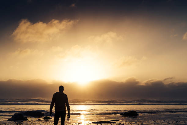 istock Man stood on a Beach near sunset after a run along the beach. 823934386