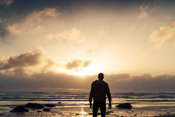istock Man stood on a Beach near sunset after a run along the beach. 823934404