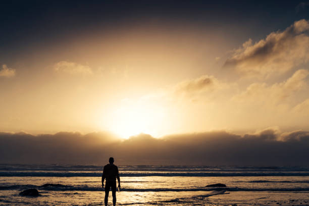 istock Man stood on a Beach near sunset after a run along the beach. 823934424
