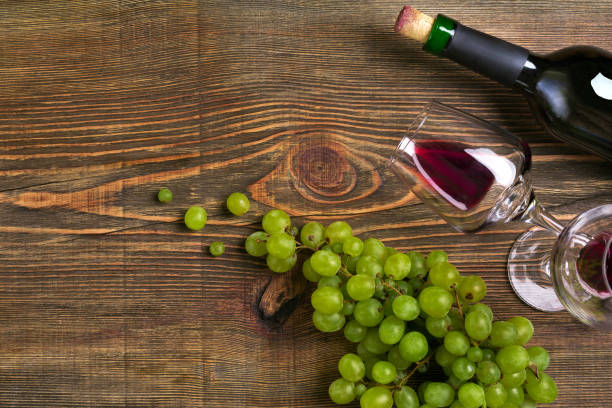 istock Two glasses, bottle of red wine and grape on a wooden table 823935672