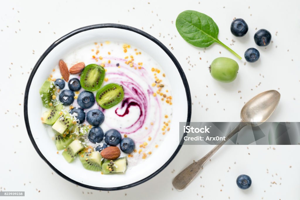 Superfood smoothie bowl Smoothie Bowl With Superfoods: acai berry, blueberry, kiwi, almond, coconut, bee pollen and baby spinach. Top view on White background Yogurt Stock Photo