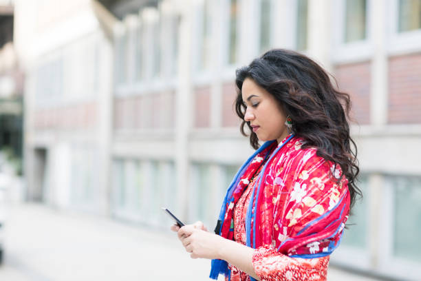 istock young hispanic woman texting in the street 823960104