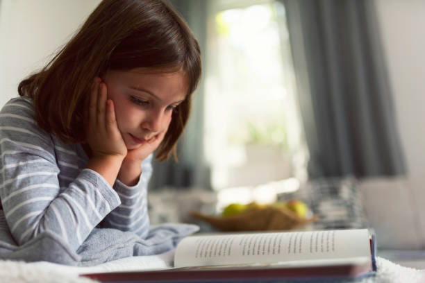 istock Cute young girl reading book at home 823962770