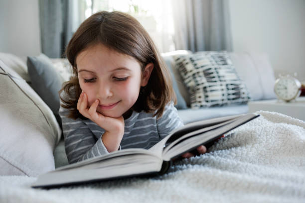 istock Cute young girl reading book at home 823962822