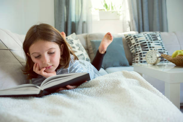 istock Cute young girl reading book at home 823963274