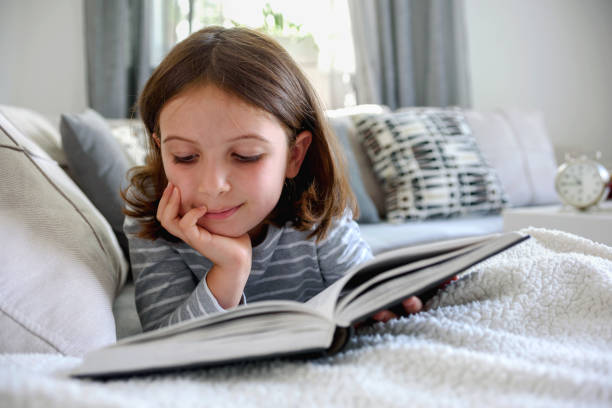 istock Cute young girl reading book at home 823963546