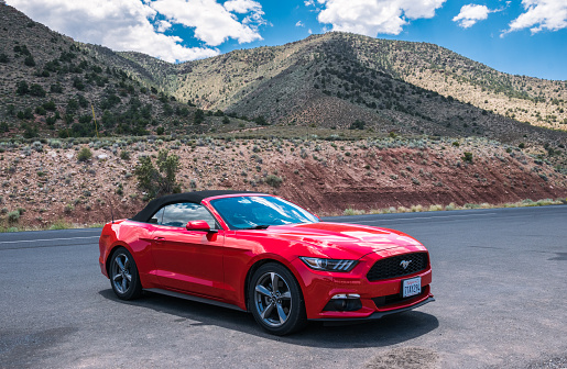 Grand Canyon Village, Arizona, USA - June 20, 2017: Red cabriolet car Ford Mustang in Crand Kenyon Village, Grand Canyon National Park, Arizona, USA. A trip to the US National Parks by car. Tourist attractions in the USA