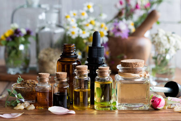 Selection of essential oils Selection of essential oils with various herbs and flowers in the background crude oil photos stock pictures, royalty-free photos & images