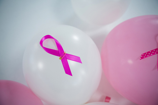 High angle view of pink Breast Cancer ribbons on balloons against white background