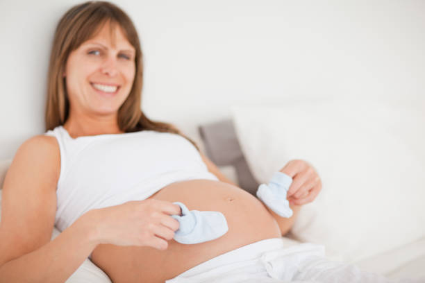 istock Attractive pregnant woman playing with little socks while lying on a bed 823979076