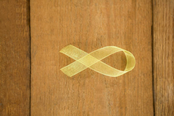 Directly above view of yellow Sarcoma Awareness ribbon on wooden table