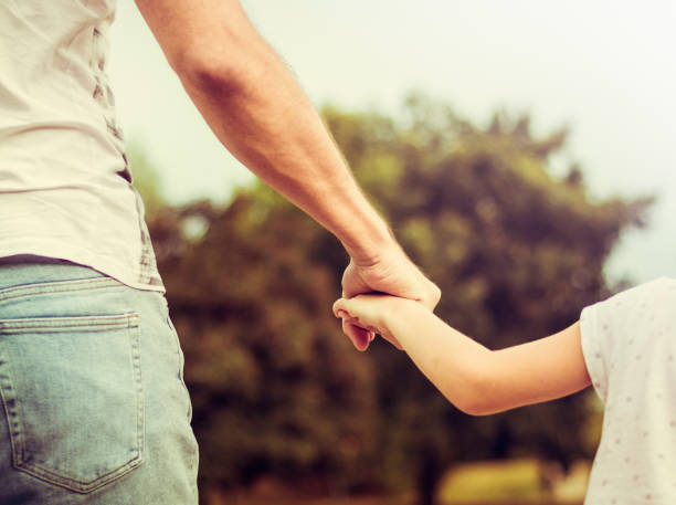 istock Father and daughter holding hands closeup 824016198