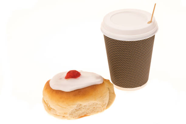 An iced bun cake and a hot drink in a disposable cup - white background