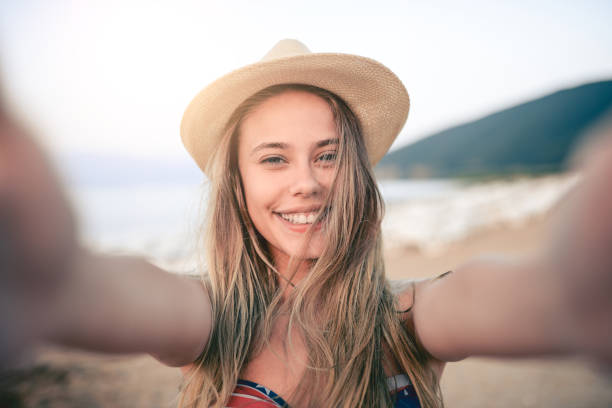 istock Smiling Young Girl With Straw Hat Taking Selfie In Summer on Beach 824017716