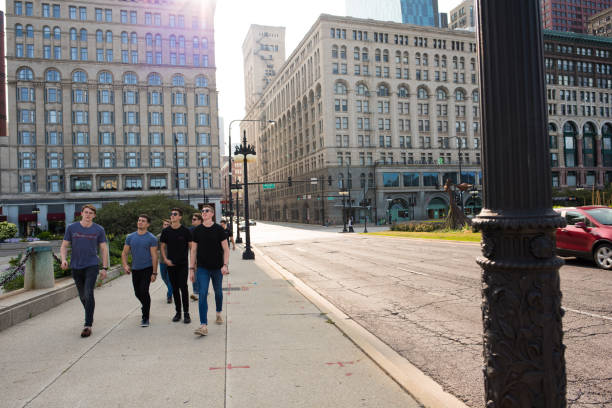 giovani amici maschi che camminano nel centro di chicago al crepuscolo - pantaloni aderenti foto e immagini stock