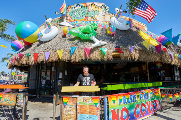 bartender at local LGBT hangout is cleaning outdoor area in anticipation of early lunch customers stock photo