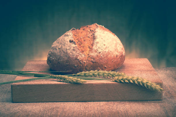 Freshly baked bread on a bread board. The image has added grain and styling.