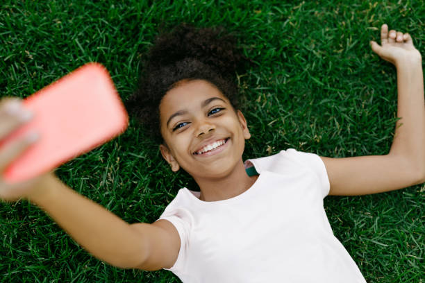istock Smiling girl lying on a grass and taking selfie 824024050